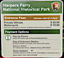 sign that says Harpers Ferry National Historical Park - Entance fees Private vehicle $20, Motorcycle $15, payment options, etc.